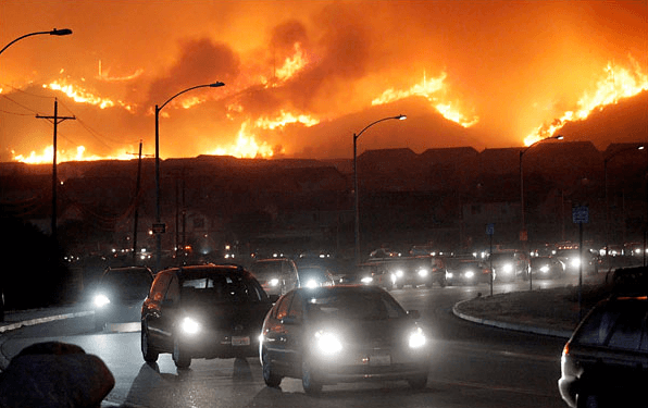 Cars Stream Along A Southern California Highway As Wildfires Rage Across The Mountains.